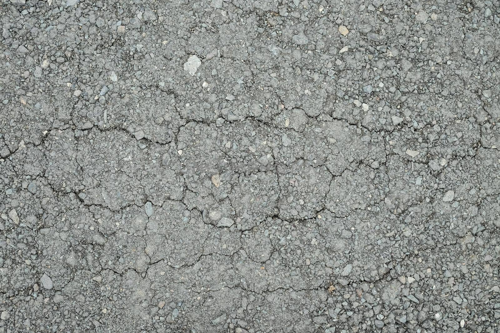 Old worn asphalt road with cracks texture.