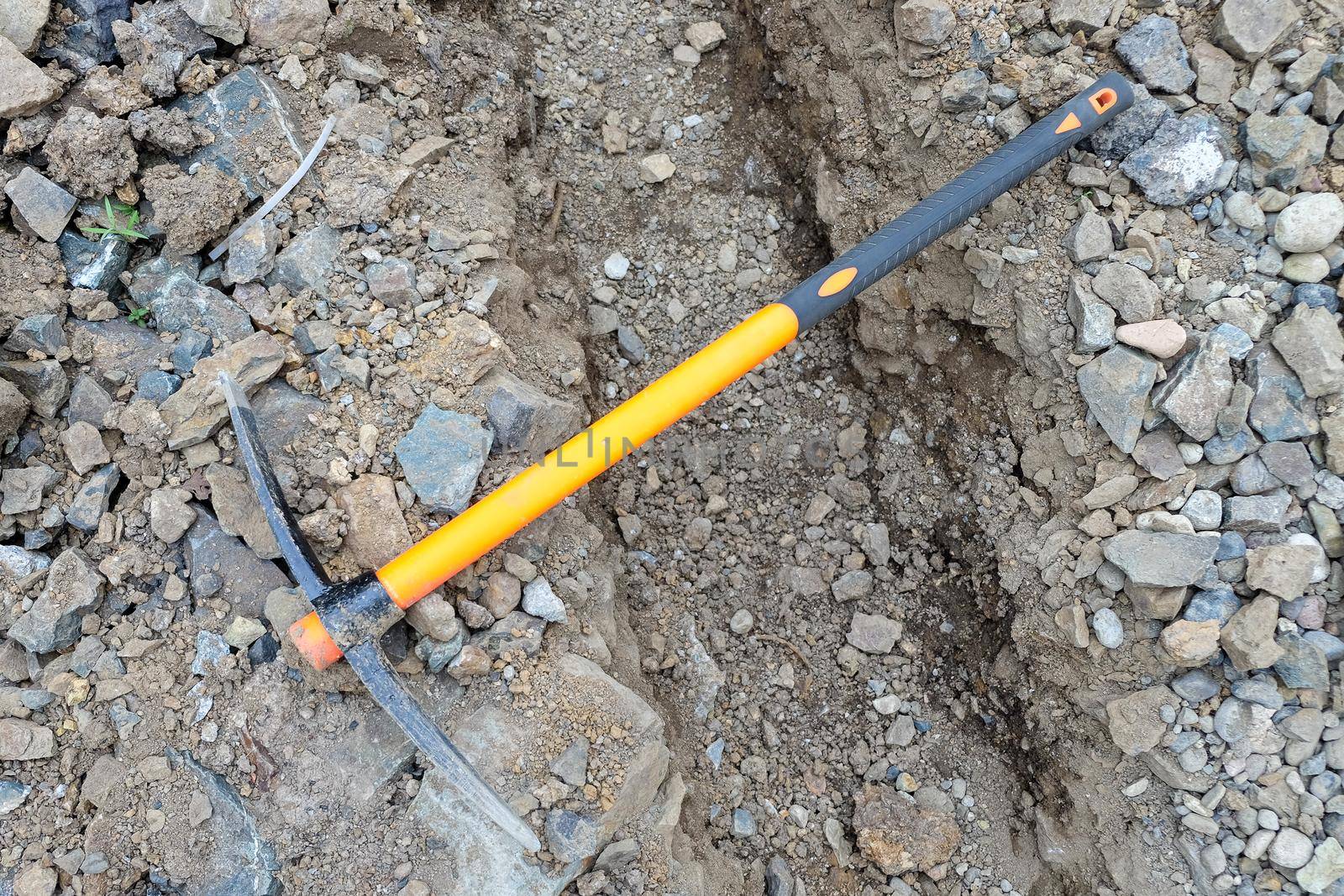 pickaxe hoe lying on the ground. hand-held percussion tool designed for working on stone, stony ground, very dense ground.