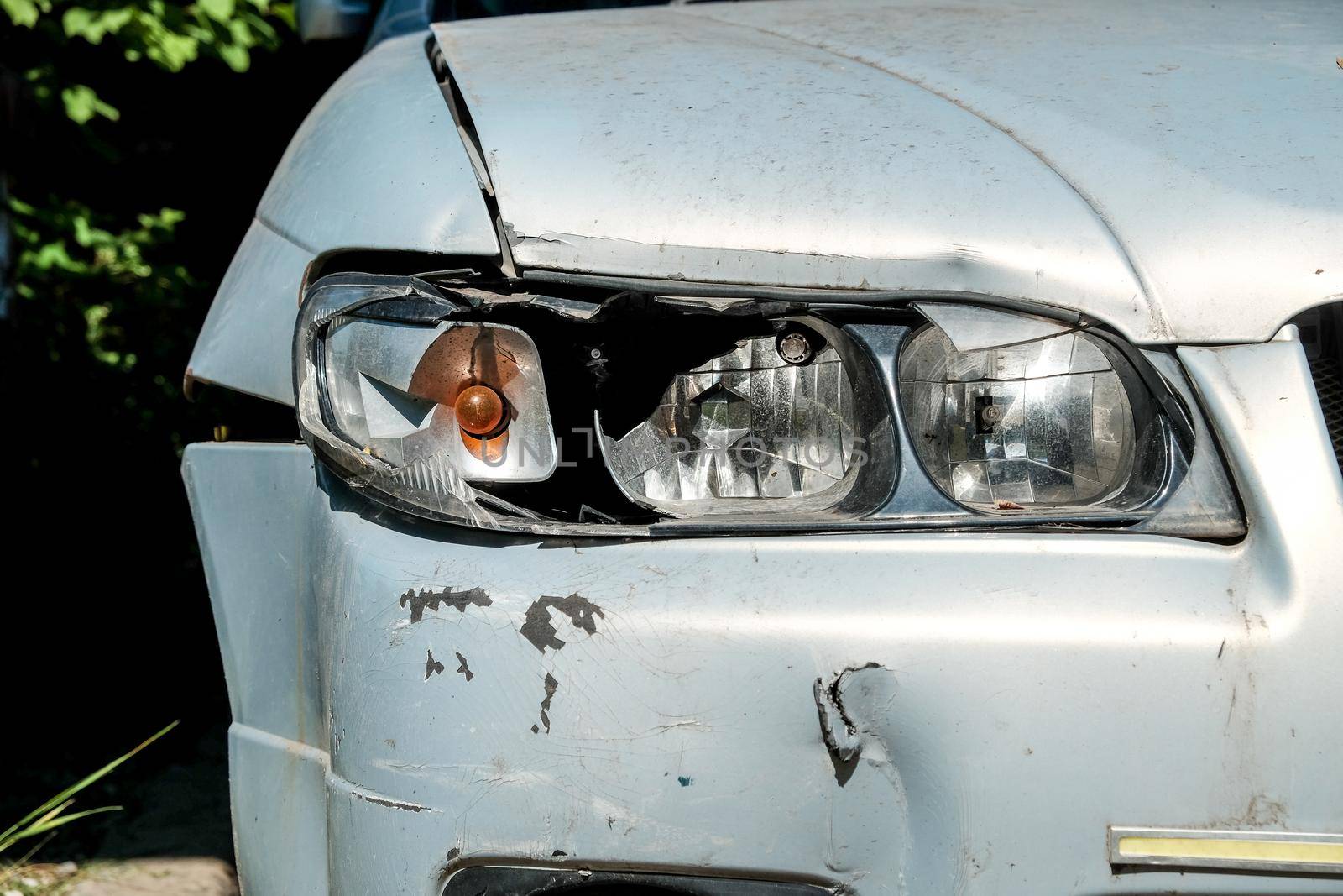 Close-up of a broken headlight on a gray car on a sunny day. Crash concept.