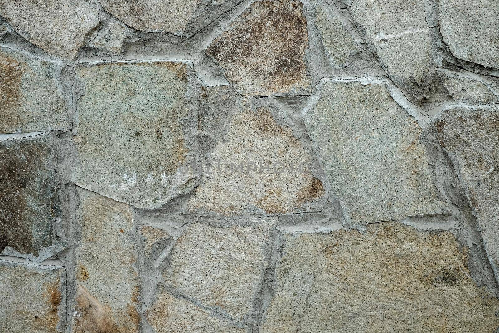 Wall texture of natural chipped stone with cement joints. Decorative stone background. Cobblestone pavement close up