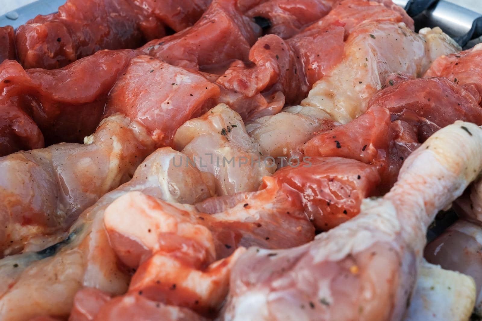 Raw pork skewers and chicken thighs cut into pieces and on skewers closeup.