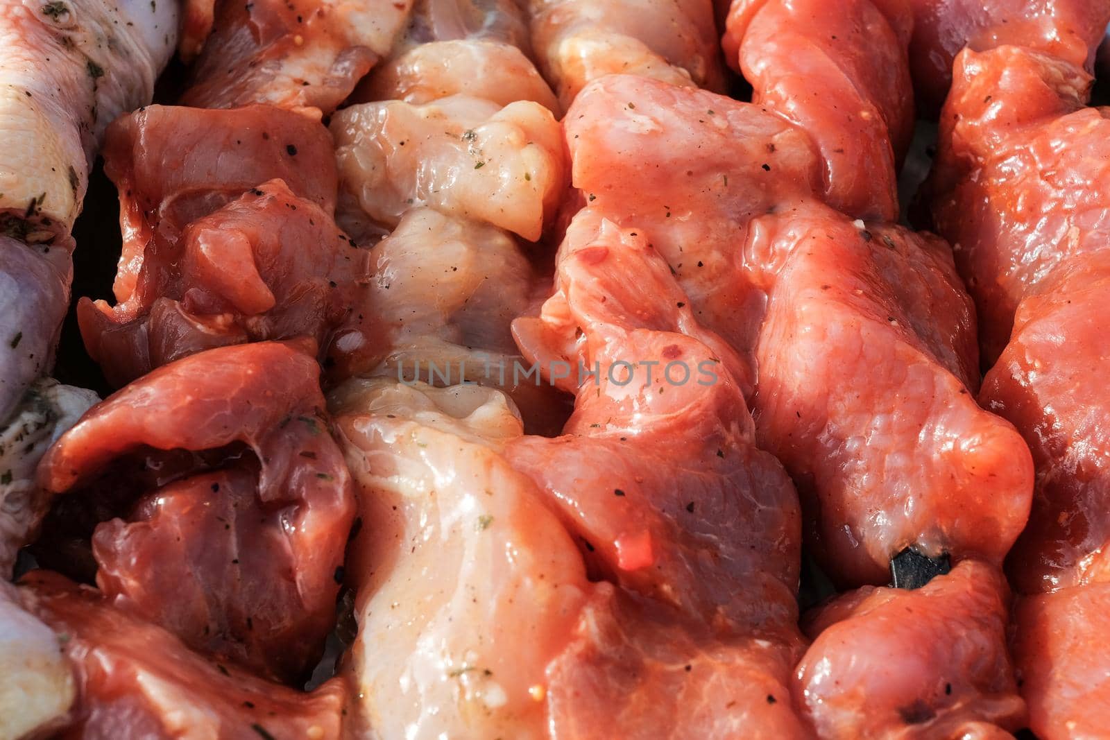 Raw pork skewers and chicken thighs cut into pieces and on skewers closeup.