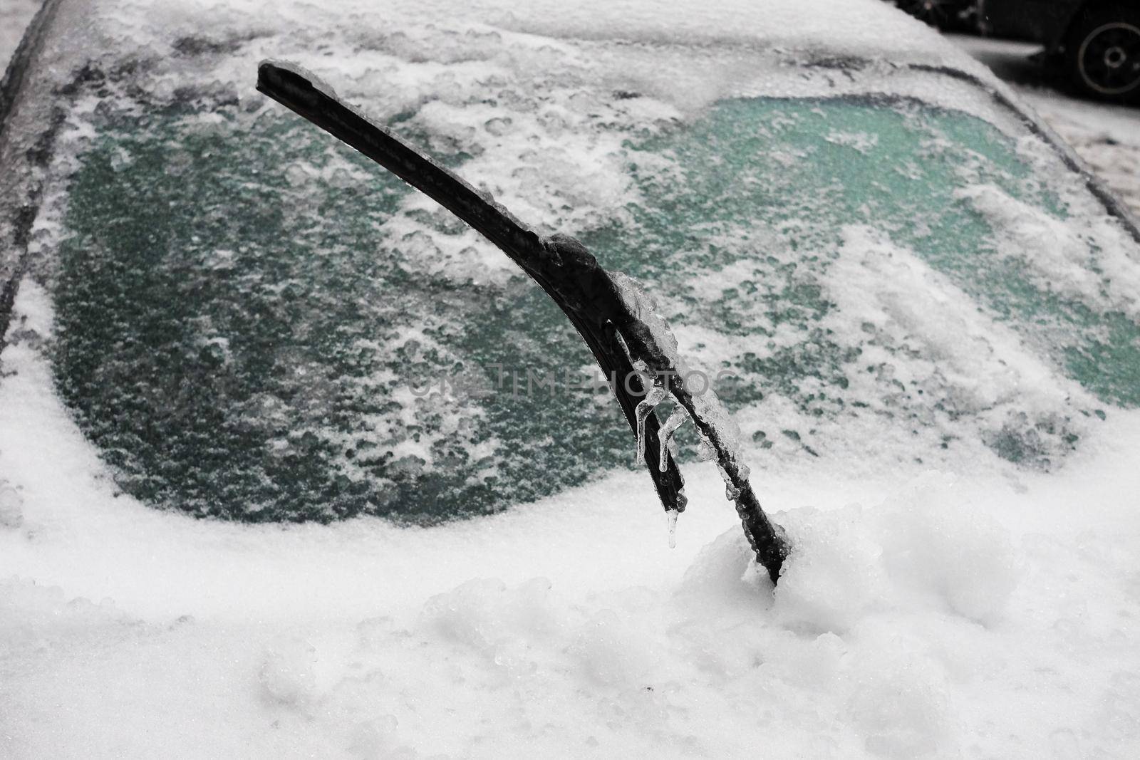 Ice covered car window close up. Car covered with ice and icicles after freezing rain. wiper covered with ice, ice storm.