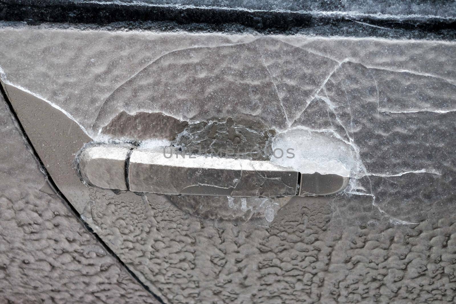 Frozen car door closeup, icicles, ice crystals, jammed lock.
