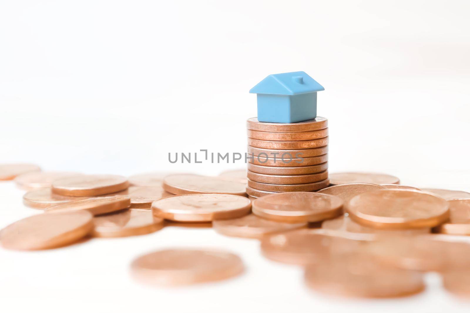 Blue toy house money coins stack on white background. Mini house model on stack coins pile money home loan concept for business property investment in real estate mortgage rates increase profit margin by synel