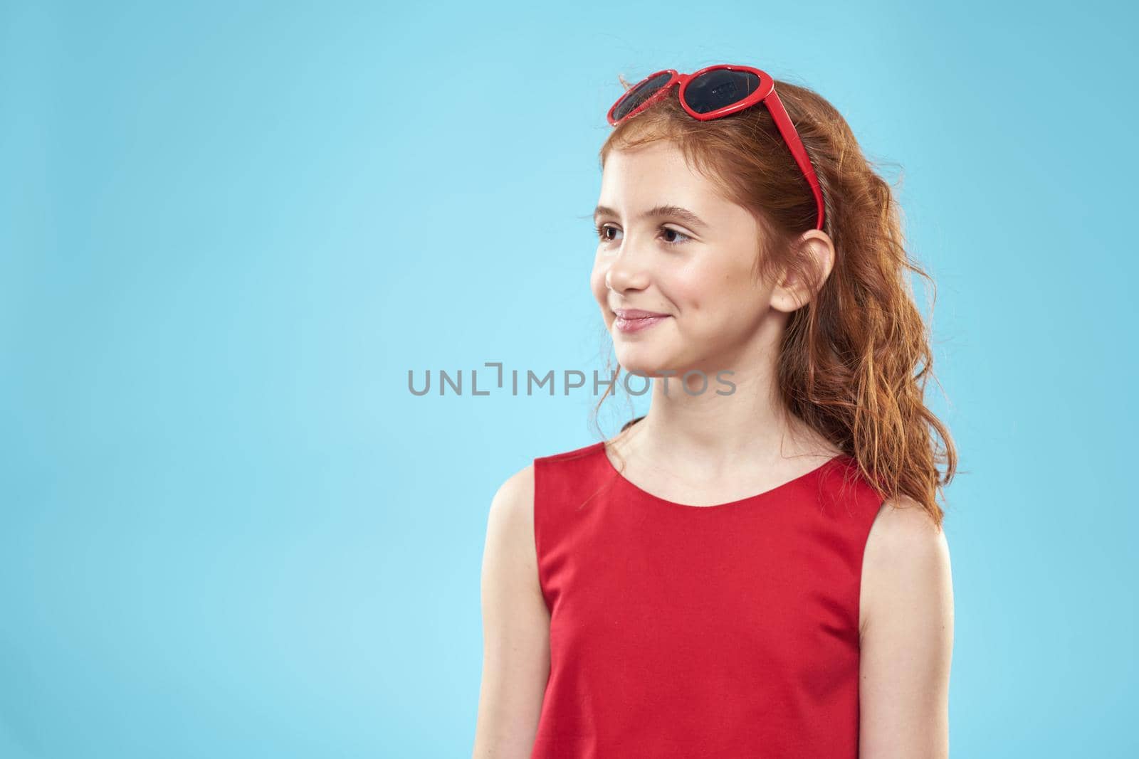 girl with curly hair sunglasses red dress and childhood fun blue background by SHOTPRIME