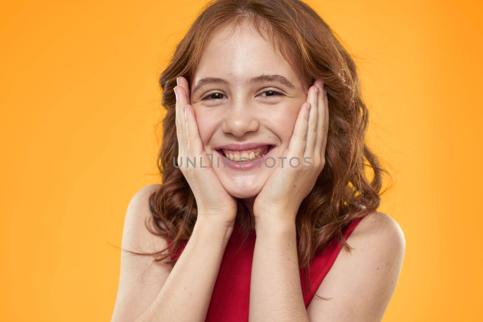Girl with curly hair red dress fun childhood emotions yellow background. High quality photo