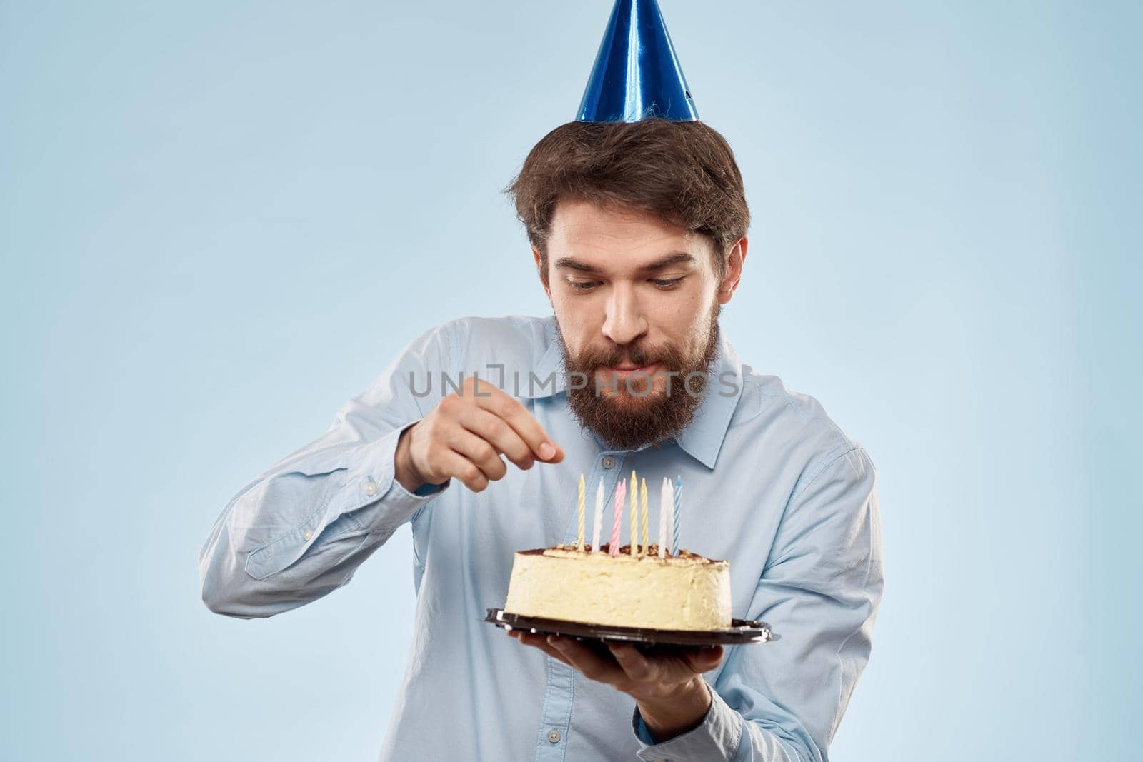 cake in a plate and birthday man with a cap on his head blue backgroun. High quality photo