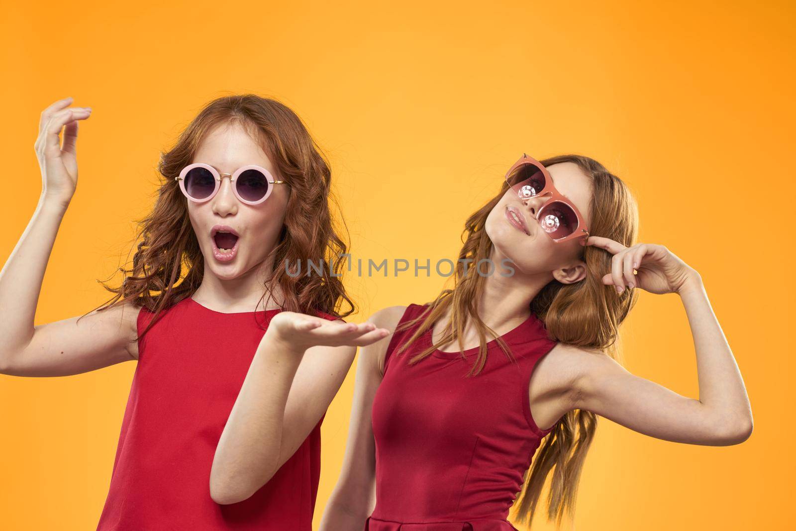 Two sisters and fun sunglasses fashion Friendship yellow background family. High quality photo