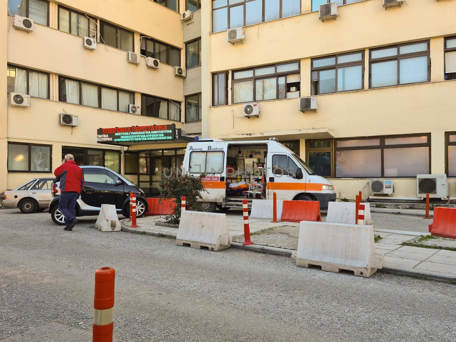 Day view of Hellenic public clinic with parked ambulance outside.