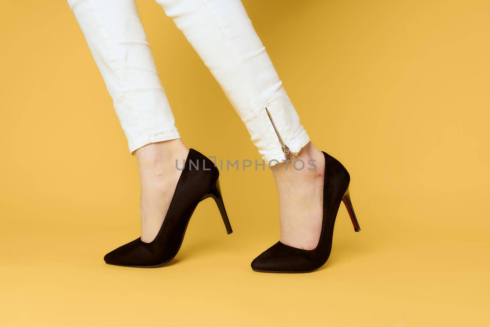 Female legs black shoes fashion attractive look white jeans yellow background by SHOTPRIME