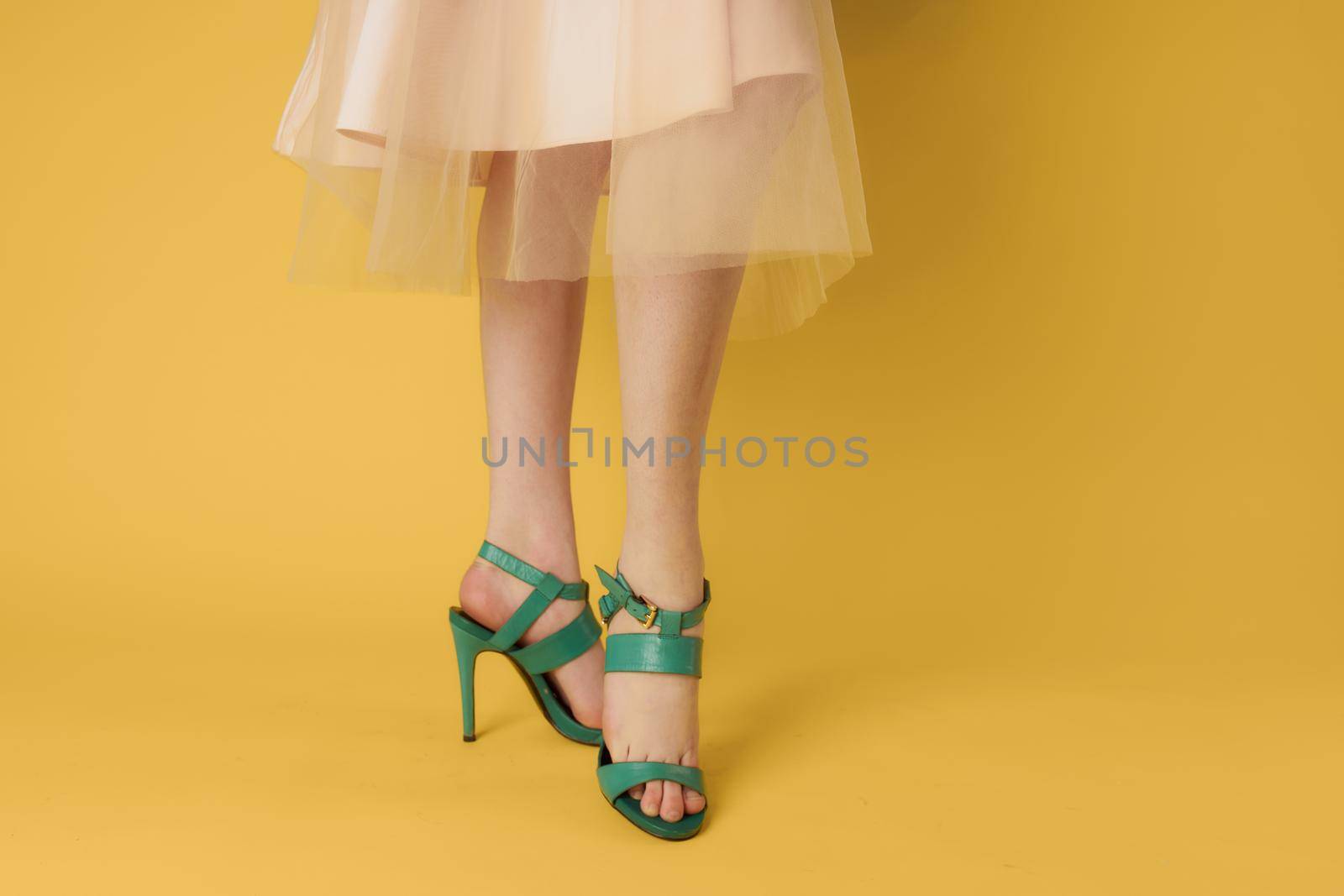 Female feet green shoes elegant style fashionable shoes yellow background. High quality photo