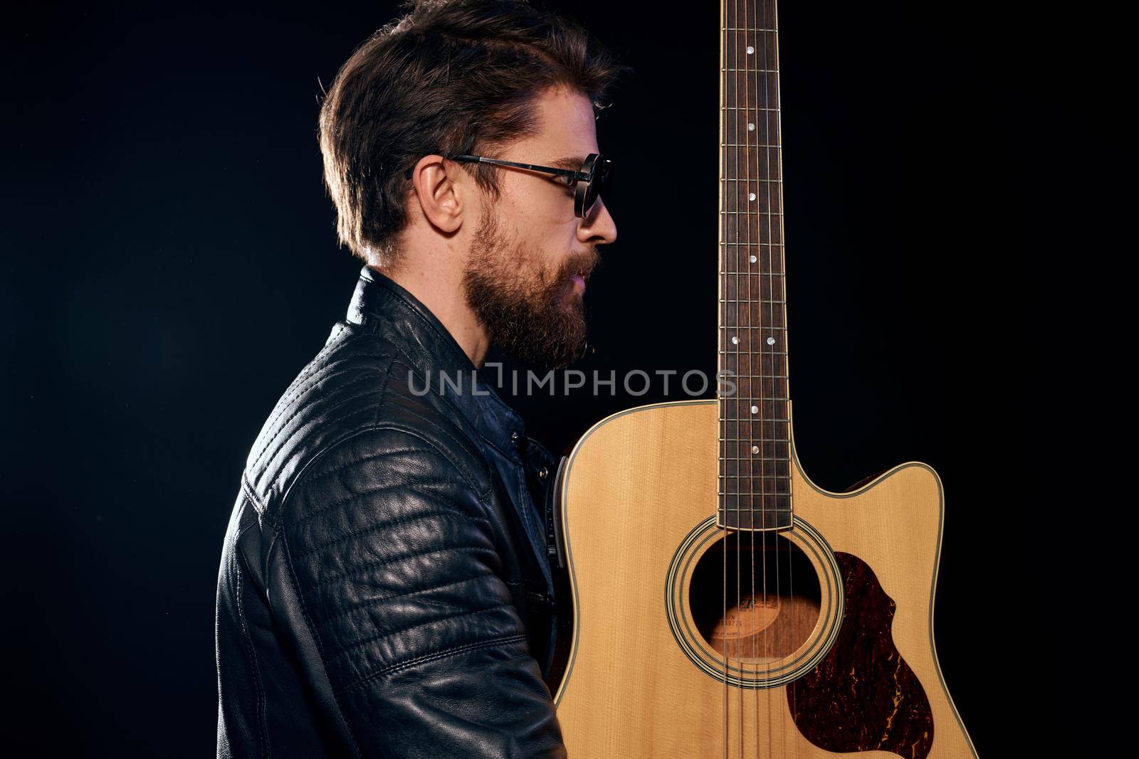 A man with a guitar in his hands leather jacket music performance rock star modern style dark background by SHOTPRIME