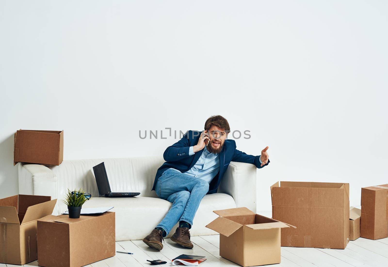 a man sitting on the couch talking on the phone an official box of things. High quality photo