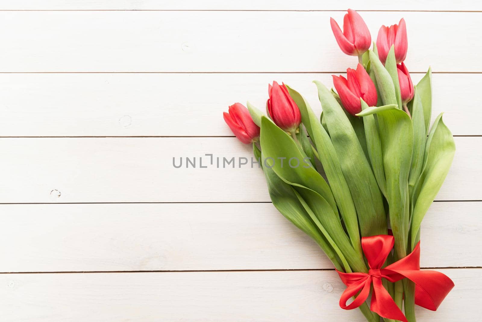 Bunch of spring tulips over white wooden background, top view flat lay