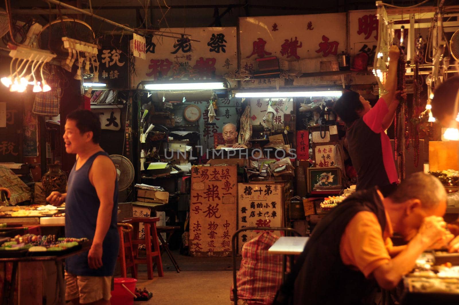 HONG KONG - 21th FEBRUARY, 2015: View of Glowing dark oriental jade market with hieroglyphs on signboards and people in light of lamps. Chinese sellers of jewelry souvenirs.