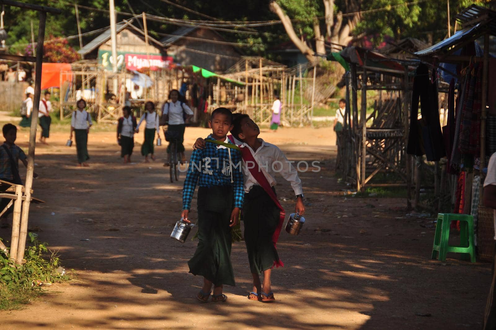 INLE, MYANMAR - NOVEMBER 29, 2015: Ethnic kids after school in village, View of ethnic pupils walking in rural village after school