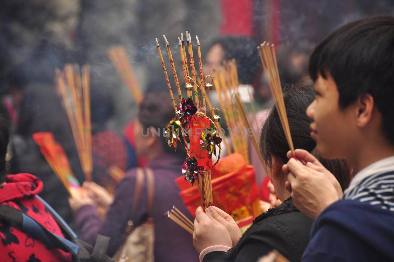 HONG KONG - 22th FEBRUARY, 2015: Crowd of people with aromatic sticks near temple, View of crowded square of people carrying burning sticks in front of Wong Tai Sin temple. Celebrating New Year.