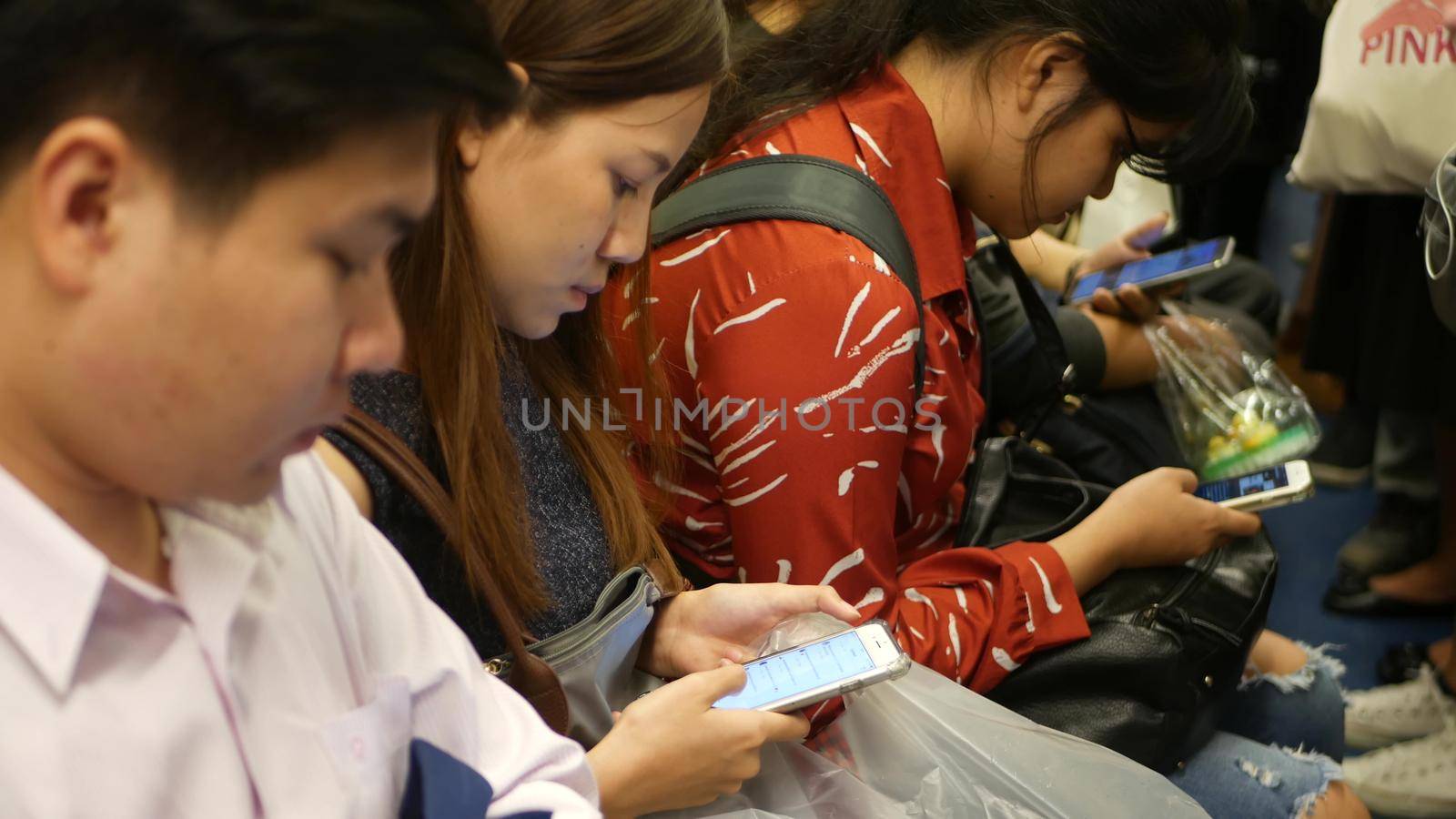 BANGKOK, THAILAND - 18 DECEMBER, 2018: Passenger at BTS Skytrain station in Bangkok Thailand, everybody looking down at smartphone while waiting for the BTS skytrain by DogoraSun