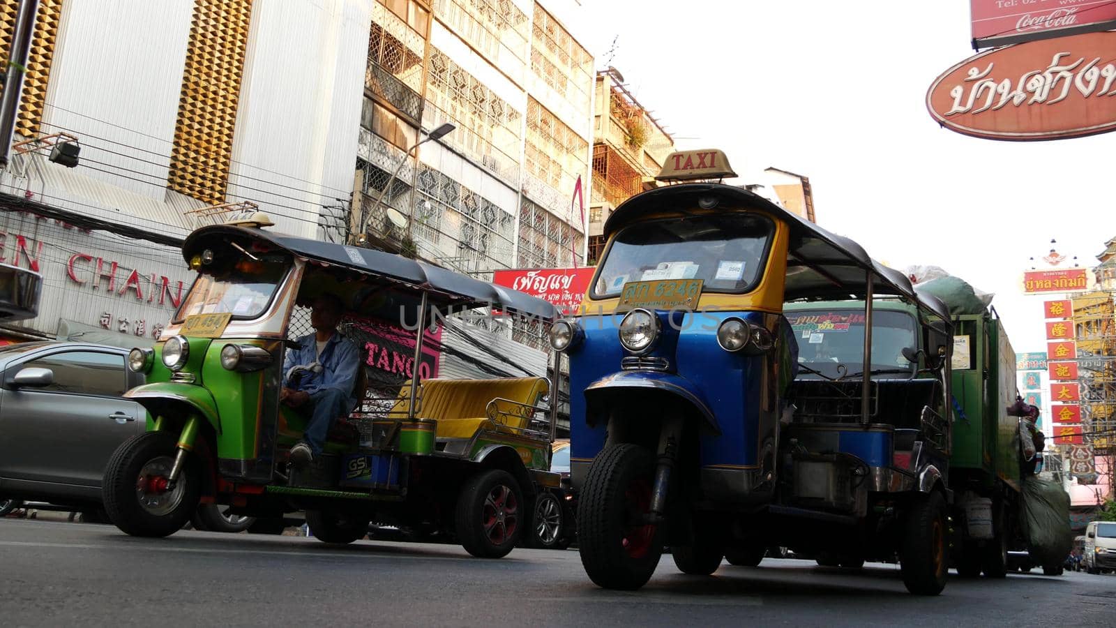 BANGKOK, THAILAND - 18 MARCH, 2019: Tuk tuks on street of Asian city. Colorful auto rickshaws riding on asphalt road on busy street of Chinatown in Bangkok. by DogoraSun