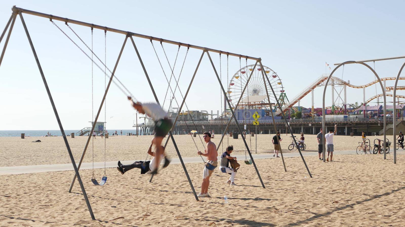 SANTA MONICA, LOS ANGELES CA USA - 28 OCT 2019: California summertime pacific ocean beach aesthetic, young people training and having fun on sports ground. Muscle beach and amusement park on pier.