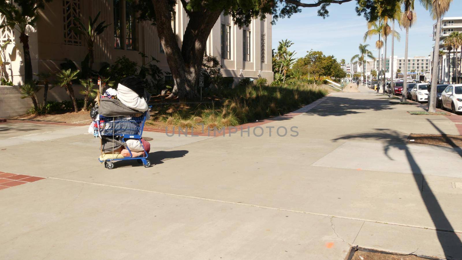 SAN DIEGO, CALIFORNIA USA - 30 JAN 2020: Stuff of homeless street people on walkway, truck on roadside. Begging problem in downtown of city near Los Angeles. Jobless beggars trolley cart on pavement.