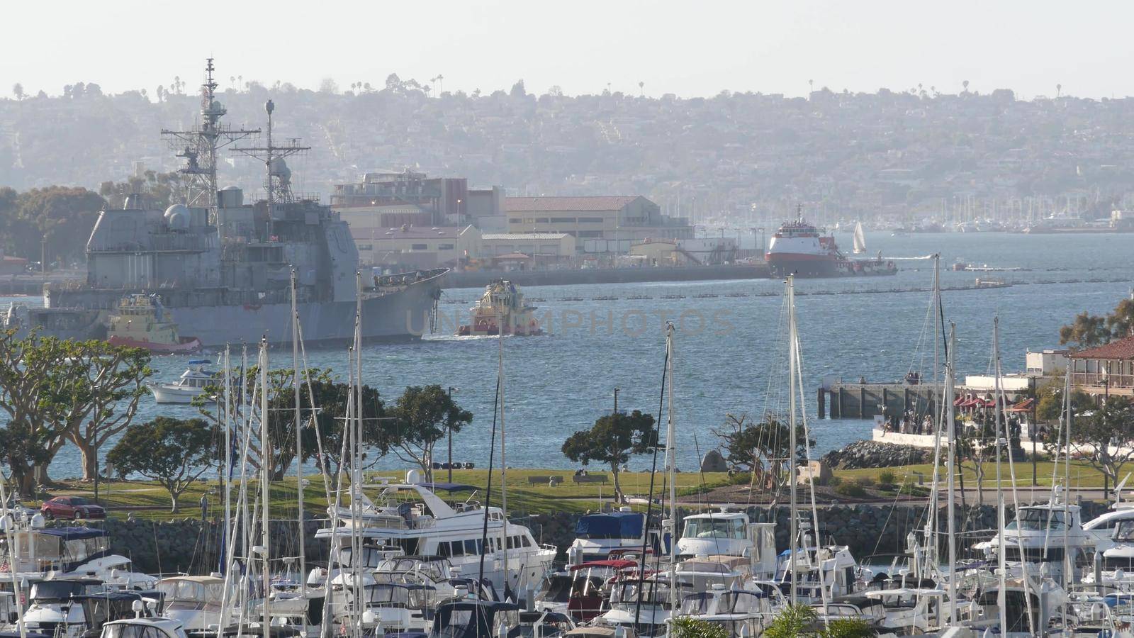 SAN DIEGO, CALIFORNIA USA - 13 FEB 2020: Tugboat pulling USS Chosin CG-65, military warship of US Navy fleet. Tug towing maritime battleship in port harbor. United States Armed Forces naval ship by DogoraSun