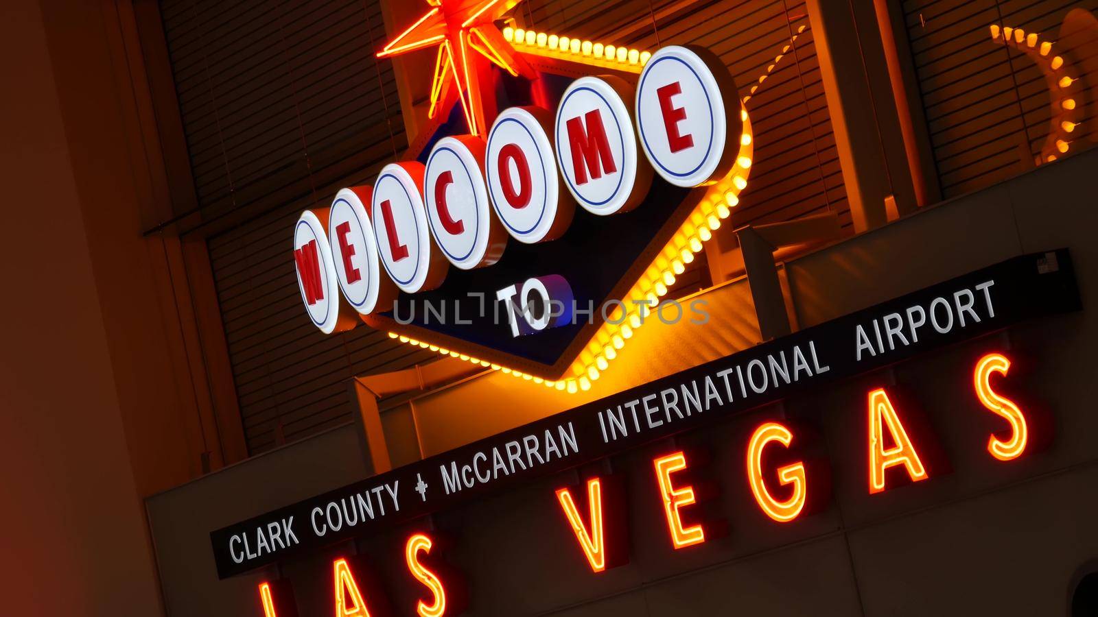 LAS VEGAS, NEVADA USA - 9 MAR 2020: Welcome to fabulous Sin City illuminated retro neon sign inside McCarran airport. Iconic greeting vintage styled signboard glowing. Gambling casino resort symbol by DogoraSun