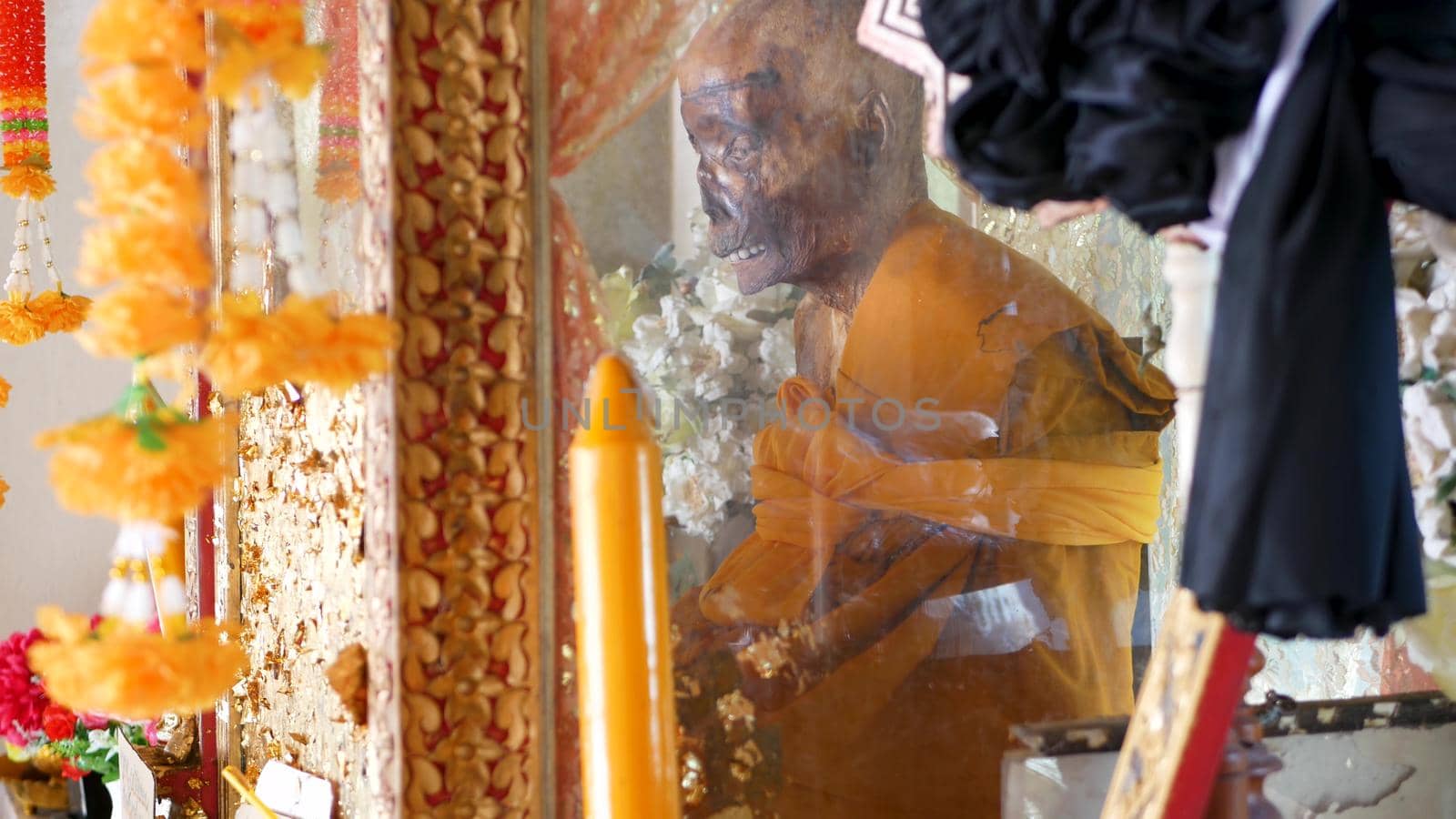 KOH SAMUI ISLAND, THAILAND - 17 JULY 2019: Wat Khiri Wongkaram Buddhist Temple. The mummified body of monk and gold leaf. Exotic tradition of storing the relics of saints who died during meditation. by DogoraSun