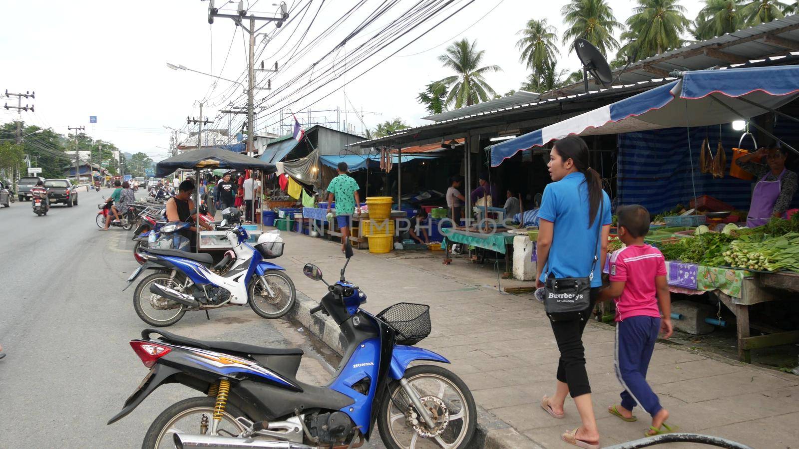 KOH SAMUI ISLAND, THAILAND - 10 JULY 2019: Food market for locals. Lively ranks with groceries. Typical daily life on the street in Asia. People go shopping for fruits vegetables, seafood and meat. by DogoraSun