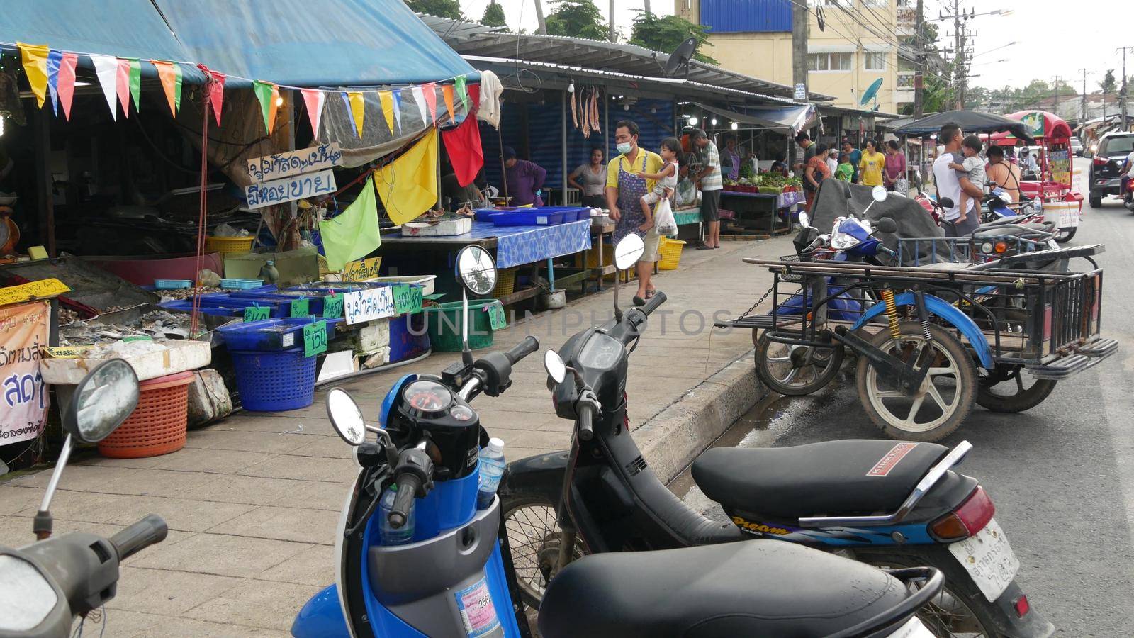 KOH SAMUI ISLAND, THAILAND - 10 JULY 2019: Food market for locals. Lively ranks with groceries. Typical daily life on the street in Asia. People go shopping for fruits vegetables, seafood and meat