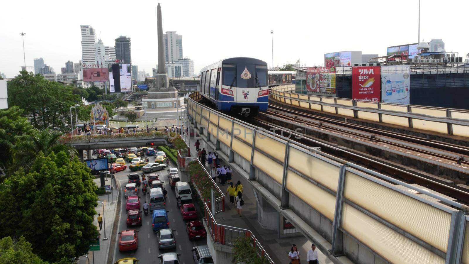 BANGKOK, THAILAND - 10 JULY, 2019: Rush hour traffic near Victory Monumet in Krungthep capital. Famous asian landmark and travel destination. Downtown modern city life. People and passengers of bts. by DogoraSun