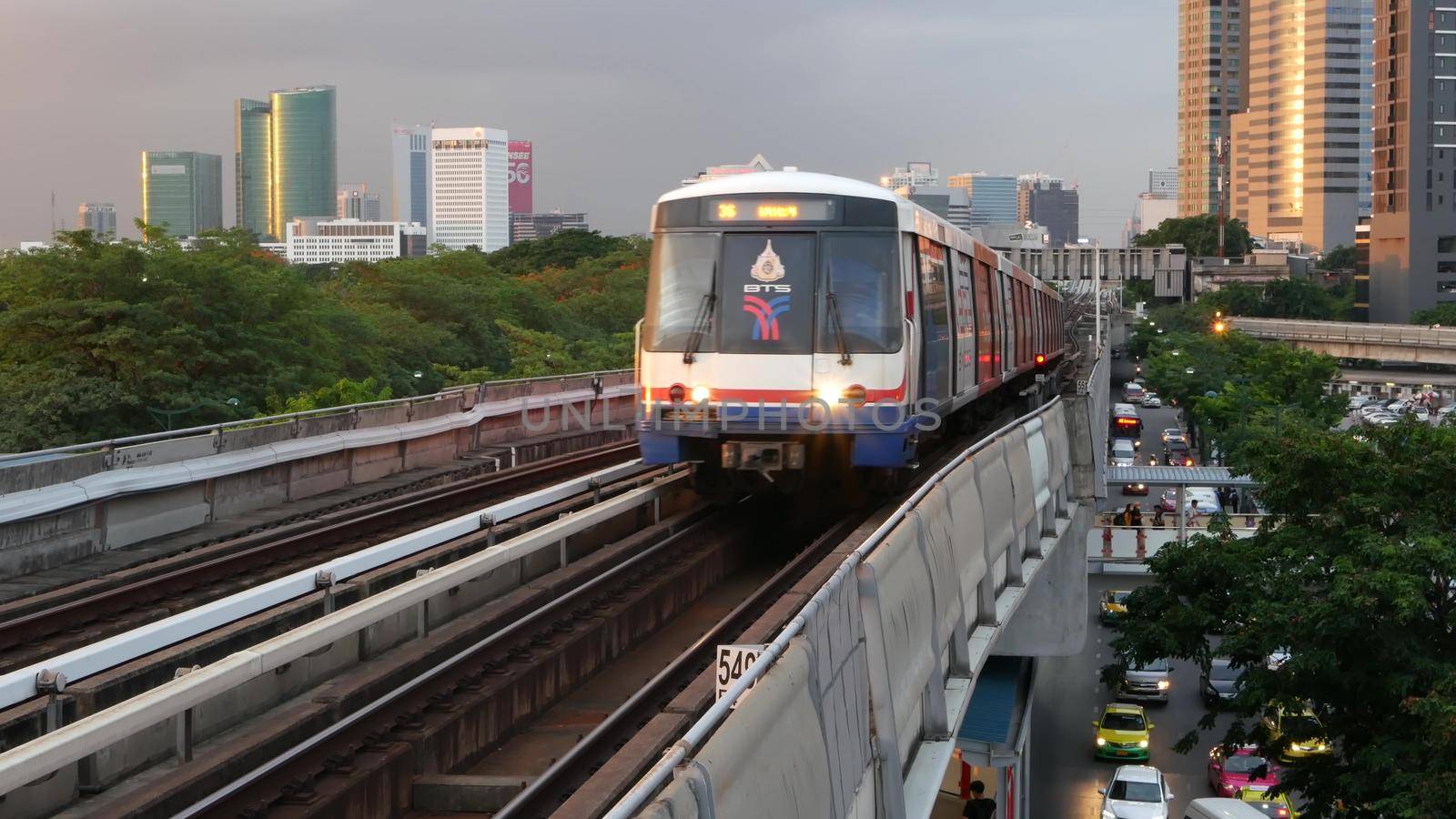 BANGKOK, THAILAND - 10 JULY, 2019: View of modern asian city from bts sky train platform. Train on metro rail road station. Public transportation in Krungtep downtown. Evening steet traffic in Asia. by DogoraSun