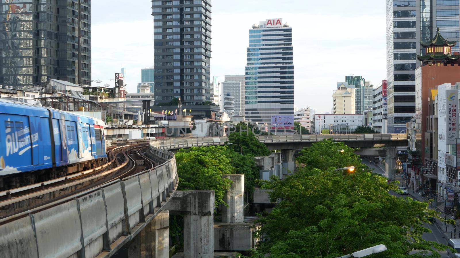 BANGKOK, THAILAND - 13 JULY, 2019: View of modern asian city from bts sky train platform. Train on metro rail road station. Public transportation in Krungtep downtown. Evening steet traffic in Asia