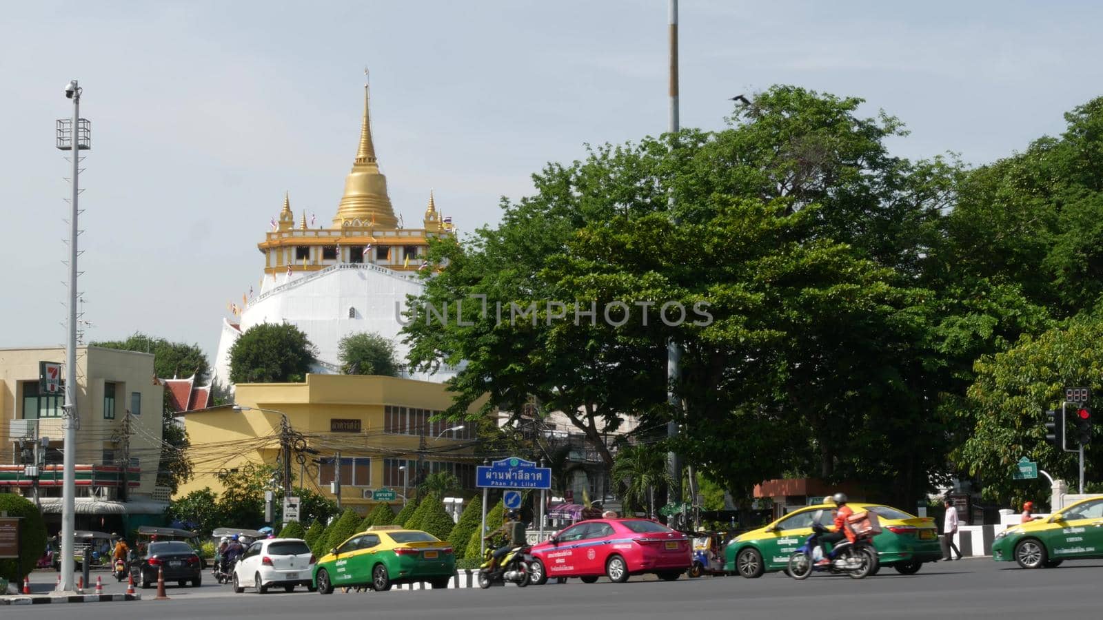BANGKOK, THAILAND - 11 JULY, 2019: Rush hour traffic near Wat Saket in capital. Famous asian landmark and travel destination. Ancient religious monastery and public transport on the road in downtown. by DogoraSun