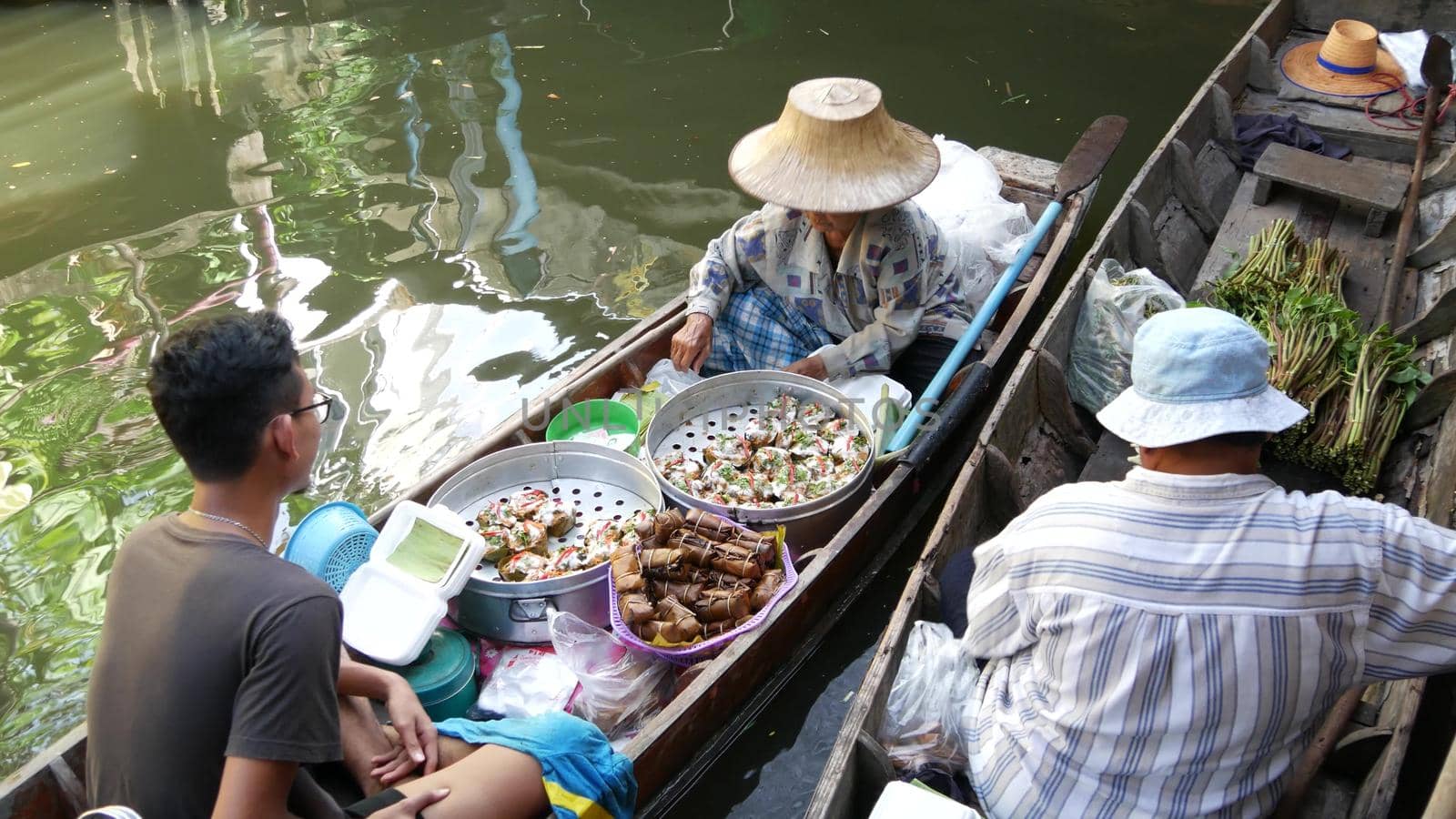 BANGKOK, THAILAND, 13 JULY 2019 Lat Mayom floating market. Traditional classic khlong river canal, local women in long-tail boats with oriental thai cusine assortment. Iconic asian street food selling by DogoraSun