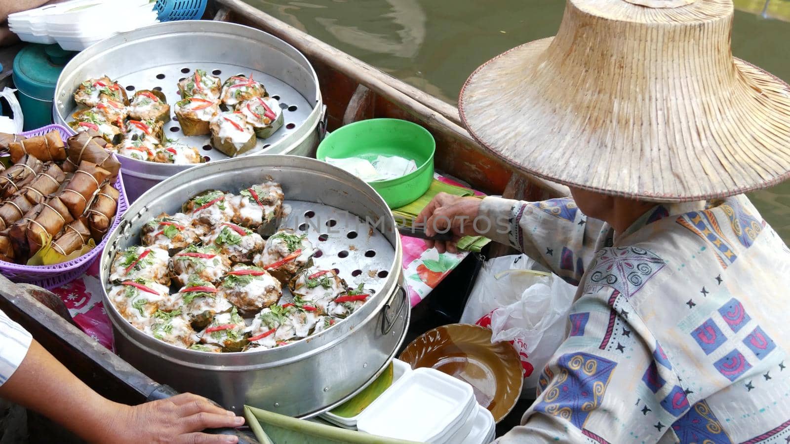 BANGKOK, THAILAND, 13 JULY 2019 Lat Mayom floating market. Traditional classic khlong river canal, local women in long-tail boats with oriental thai cusine assortment. Iconic asian street food selling by DogoraSun