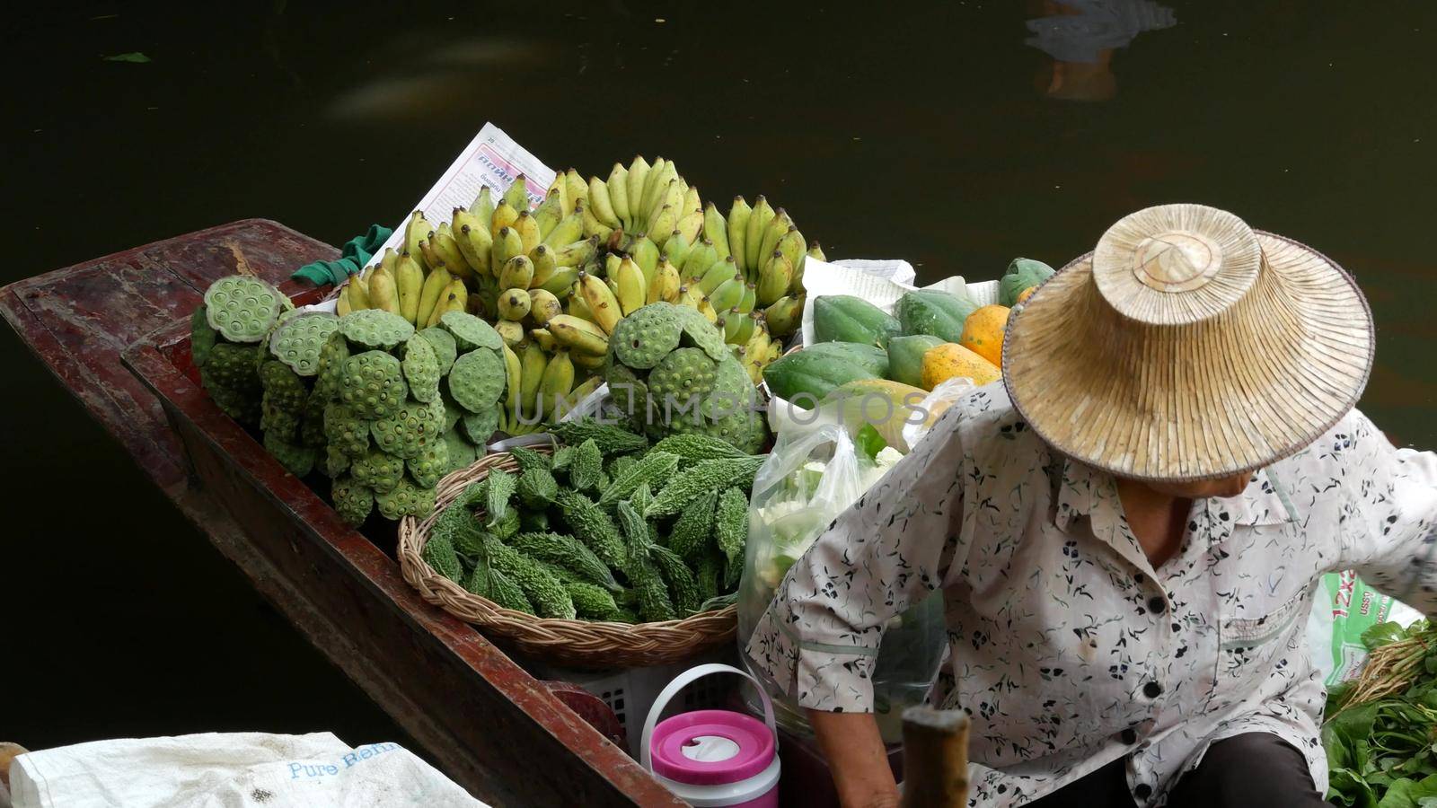 BANGKOK, THAILAND - 13 JULY 2019: Lat Mayom floating market. Traditional classic khlong river canal, local women farmers, long-tail boats with fruits and vegetables. Iconic asian street food selling. by DogoraSun