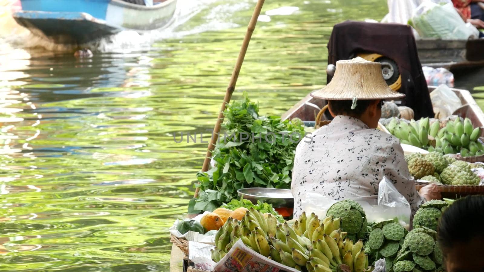 BANGKOK, THAILAND - 13 JULY 2019: Lat Mayom floating market. Traditional classic khlong river canal, local women farmers, long-tail boats with fruits and vegetables. Iconic asian street food selling