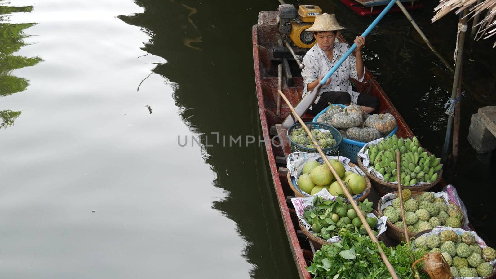 BANGKOK, THAILAND - 13 JULY 2019: Lat Mayom floating market. Traditional classic khlong river canal, local women farmers, long-tail boats with fruits and vegetables. Iconic asian street food selling. by DogoraSun