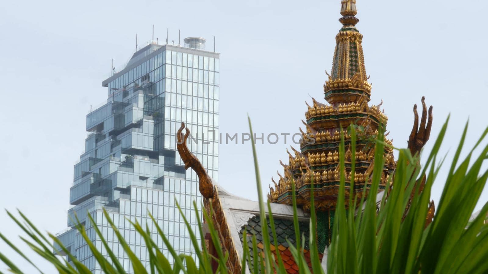 BANGKOK, THAILAND - 13 JULY, 2019: Conceptual contrast of oriental old traditional ancient temple and modern new futuristic Mahanakhon skyscraper. Classic buddhist wat compared to urban cityscape