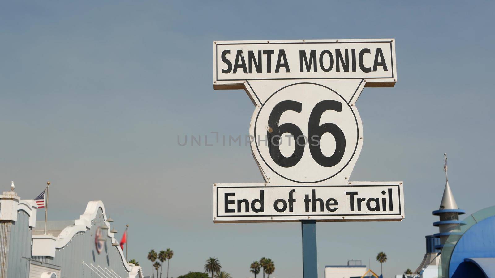 SANTA MONICA, LOS ANGELES, USA - 28 OCT 2019: Historic route 66, famous vintage california trip symbol. Pier of pacific ocean resort. Iconic retro road sign against the blue sky in amusement park by DogoraSun