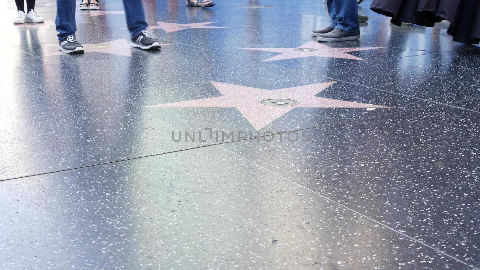 LOS ANGELES, CALIFORNIA, USA - 7 NOV 2019: Walk of fame promenade on Hollywood boulevard in LA. Pedastrians walking near celebrity stars on asphalt. Walkway floor near Dolby and TCL Chinese Theatre by DogoraSun