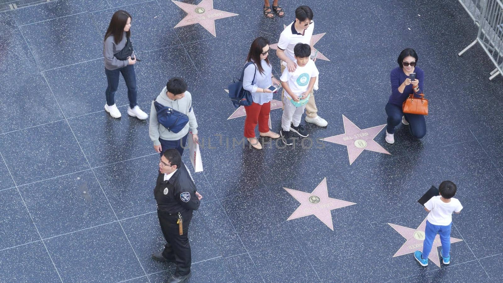 LOS ANGELES, CALIFORNIA, USA - 7 NOV 2019: Walk of fame promenade on Hollywood boulevard in LA. Pedastrians walking near celebrity stars on asphalt. Walkway floor near Dolby and TCL Chinese Theatre.