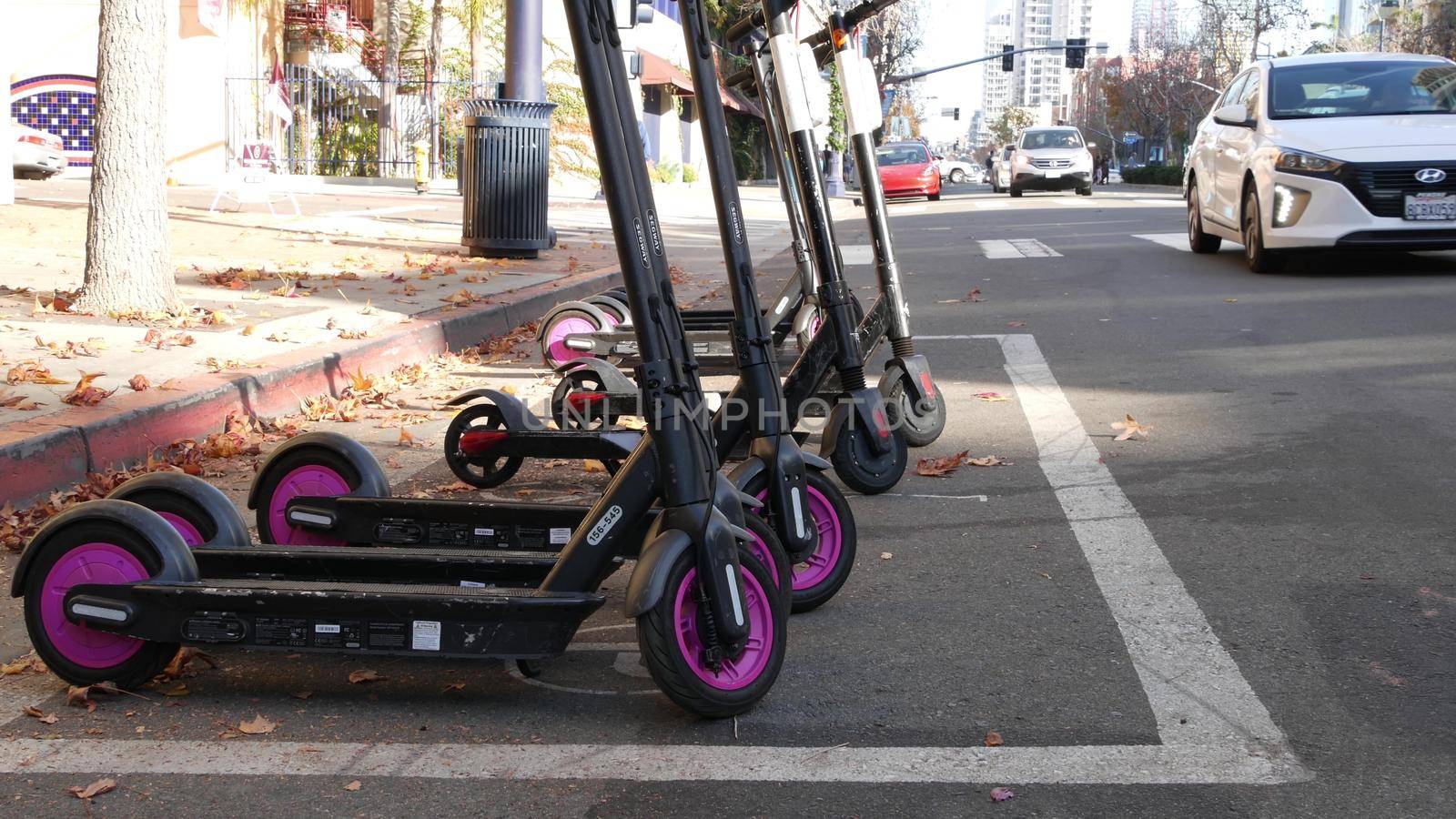 SAN DIEGO, CALIFORNIA USA - 4 JAN 2020: Row of ride sharing electric scooters parked on street in Gaslamp Quarter. Rental dockless public bikes, eco transport in city. Rent kick cycle with mobile app by DogoraSun