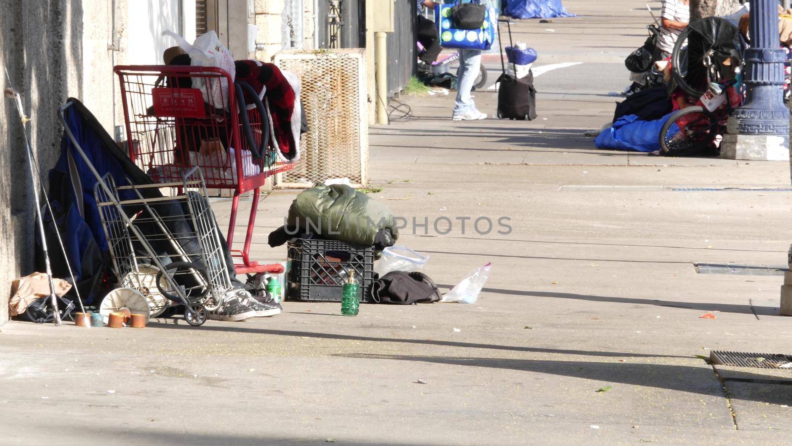 SAN DIEGO, CALIFORNIA USA - 4 JAN 2020: Stuff of homeless street people on walkway, truck on roadside. Begging problem in downtown of city near Los Angeles. Jobless beggars live on pavements by DogoraSun