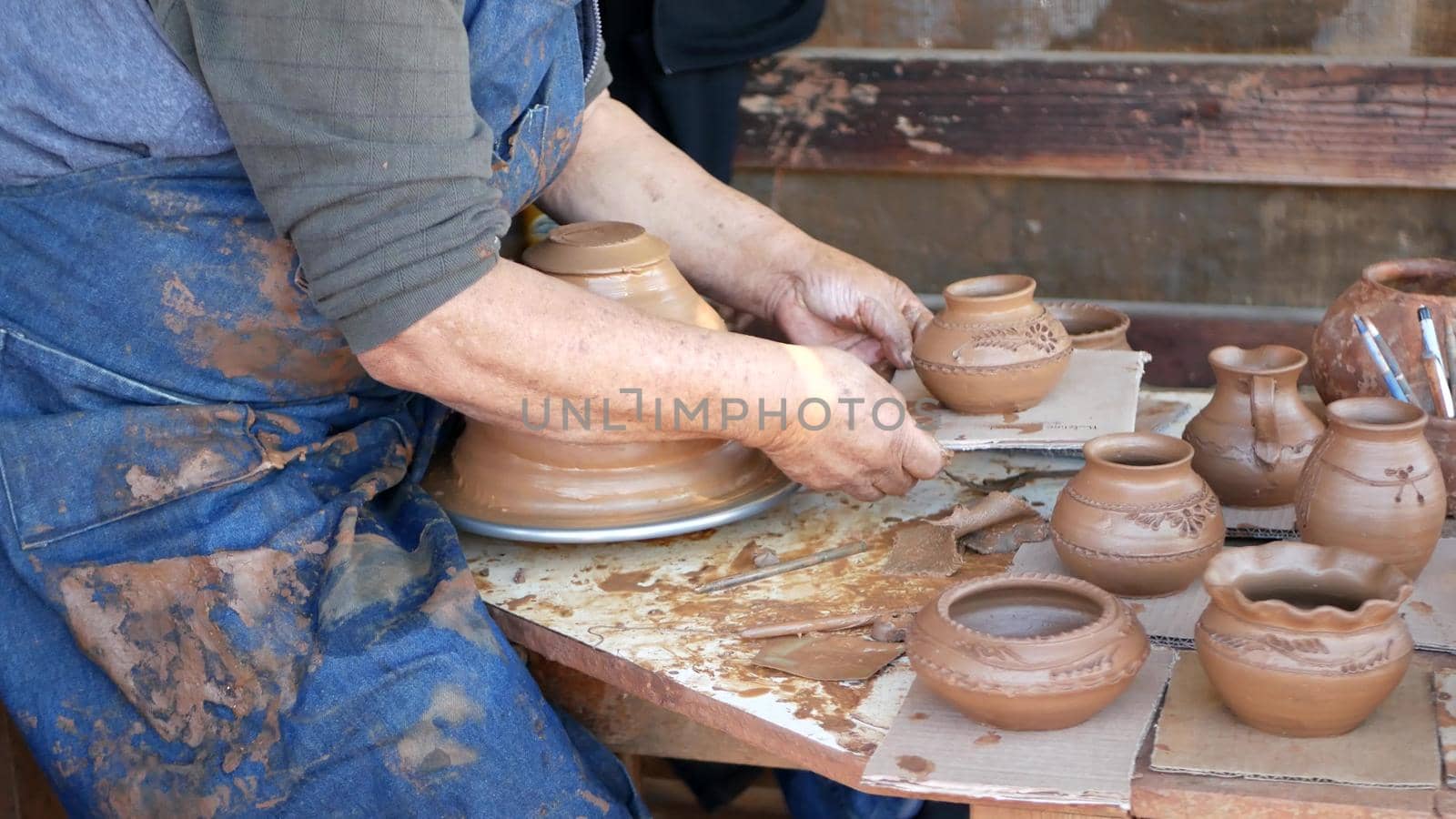 SAN DIEGO, CALIFORNIA USA - 5 JAN 2020: Potter working in mexican Oldtown, raw clay on pottery wheel. Man's hands, ceramist in process of modeling handcrafted clayware. Craftsman creating ceramic.