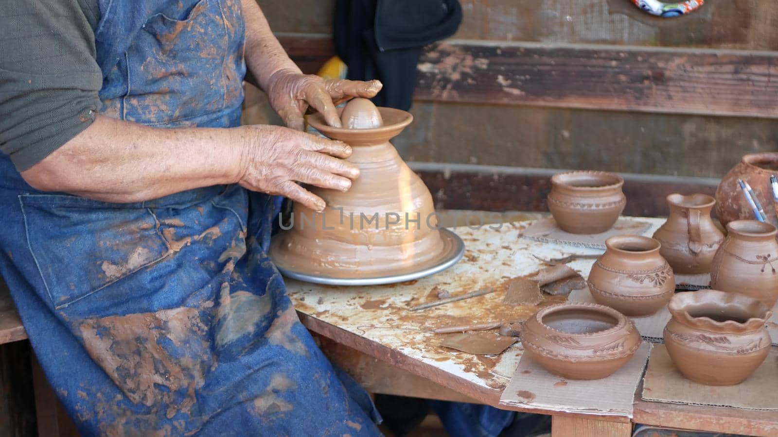 SAN DIEGO, CALIFORNIA USA - 5 JAN 2020: Potter working in mexican Oldtown, raw clay on pottery wheel. Man's hands, ceramist in process of modeling handcrafted clayware. Craftsman creating ceramic.