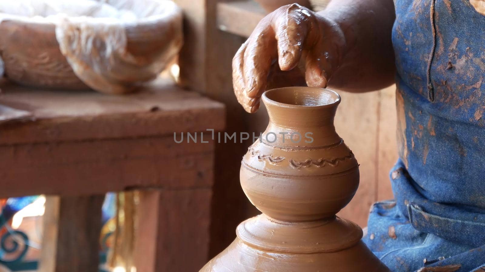 SAN DIEGO, CALIFORNIA USA - 5 JAN 2020: Potter working in mexican Oldtown, raw clay on pottery wheel. Man's hands, ceramist in process of modeling handcrafted clayware. Craftsman creating ceramic by DogoraSun