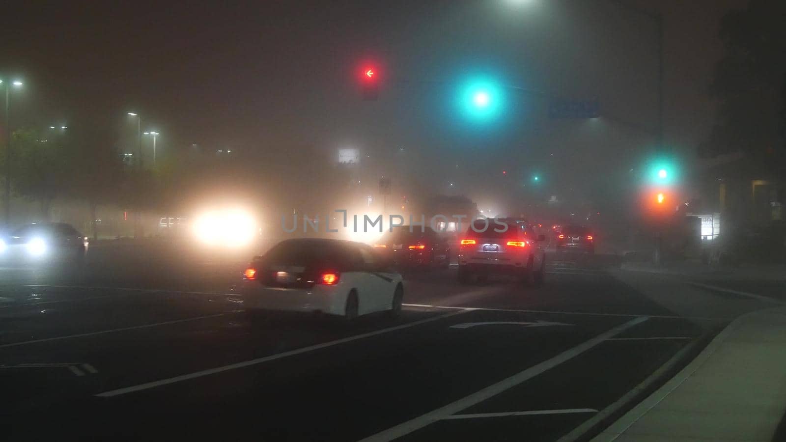 VISTA, CALIFORNIA USA - 24 JAN 2020: Marine layer, dense fog on driveway crossroad at night. June gloom, misty nebulous bad weather. Dangerous low visibility on road intersection. Car traffic safety.